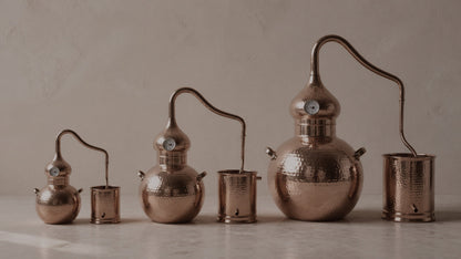 CopperHolic copper alembic stills in all three sizes side by side: 5L, 5 gallon, and 10 gallon